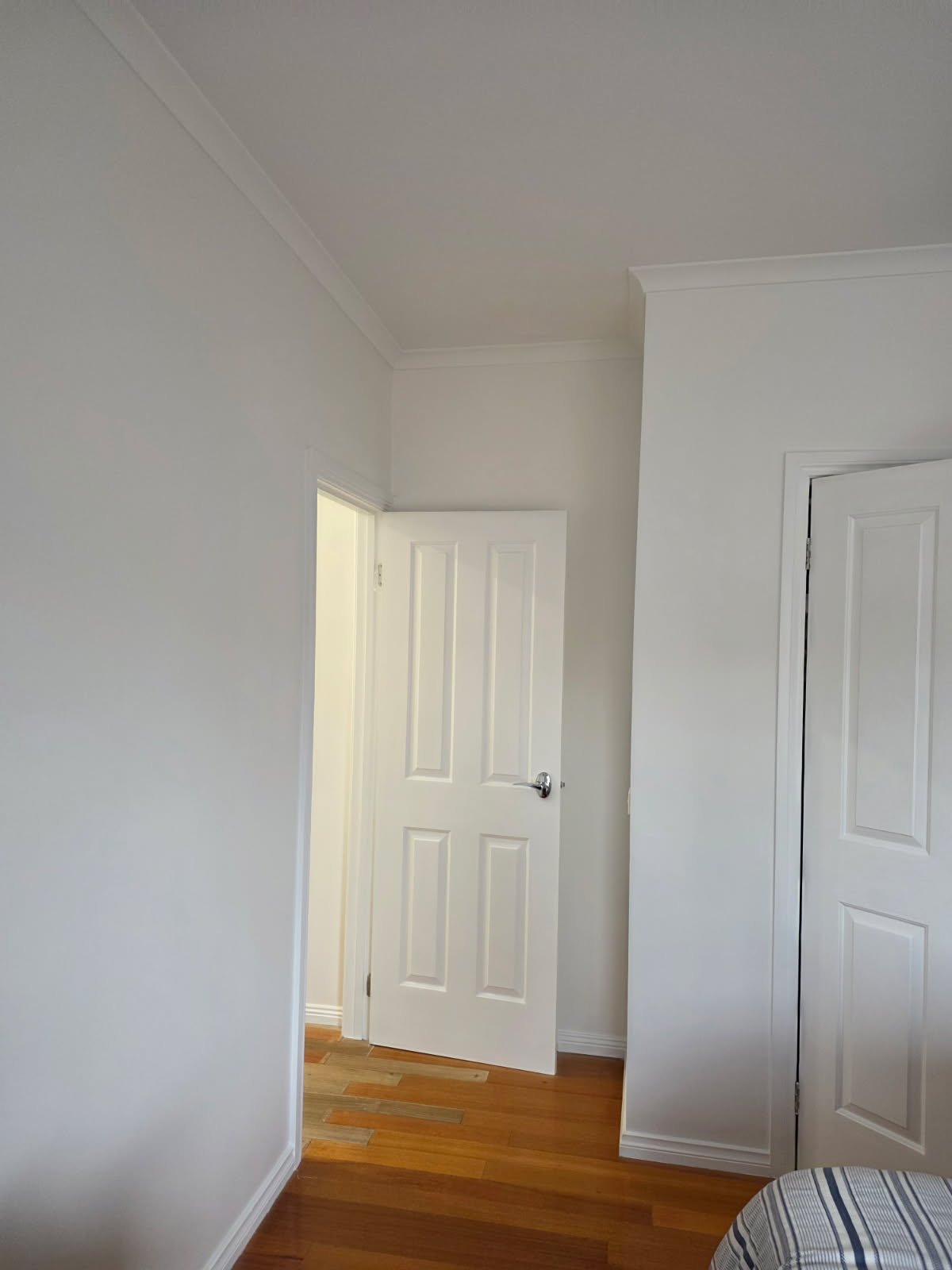 After bedroom repaint photo showing the same room finished in a soft clean neutral white