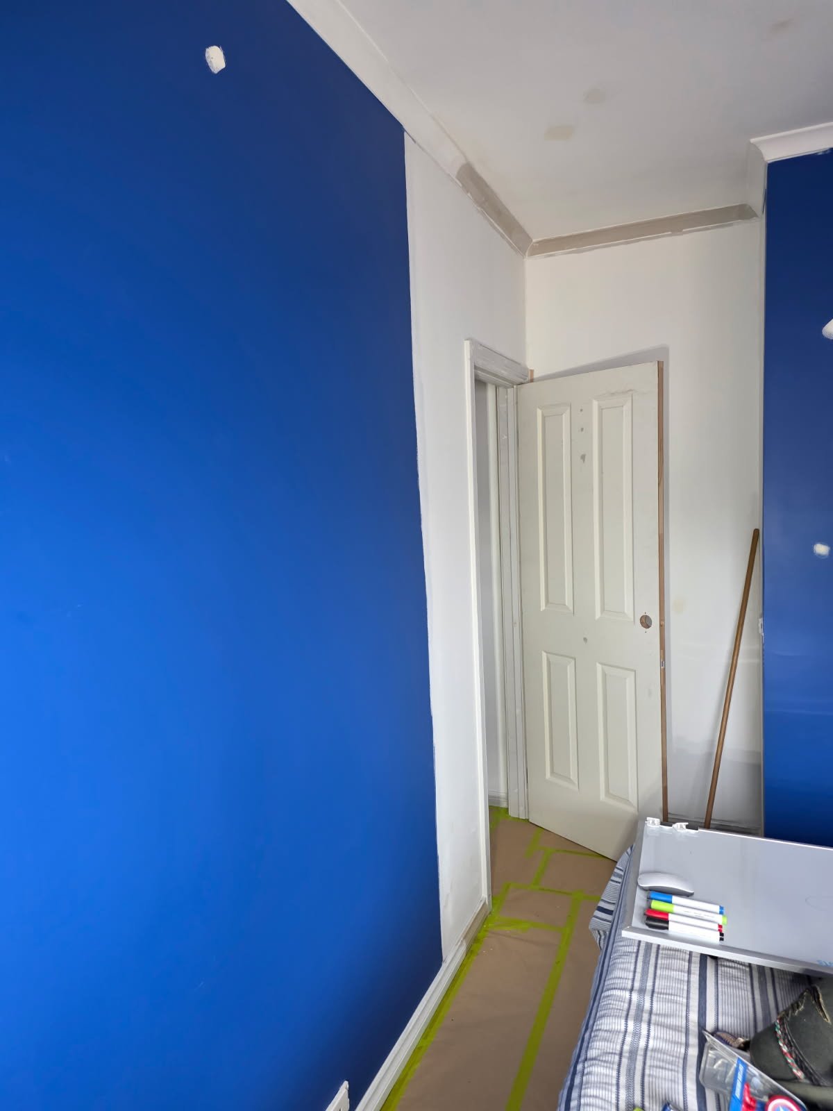 Before bedroom repaint photo showing a bold blue feature wall and patch preparation before painting