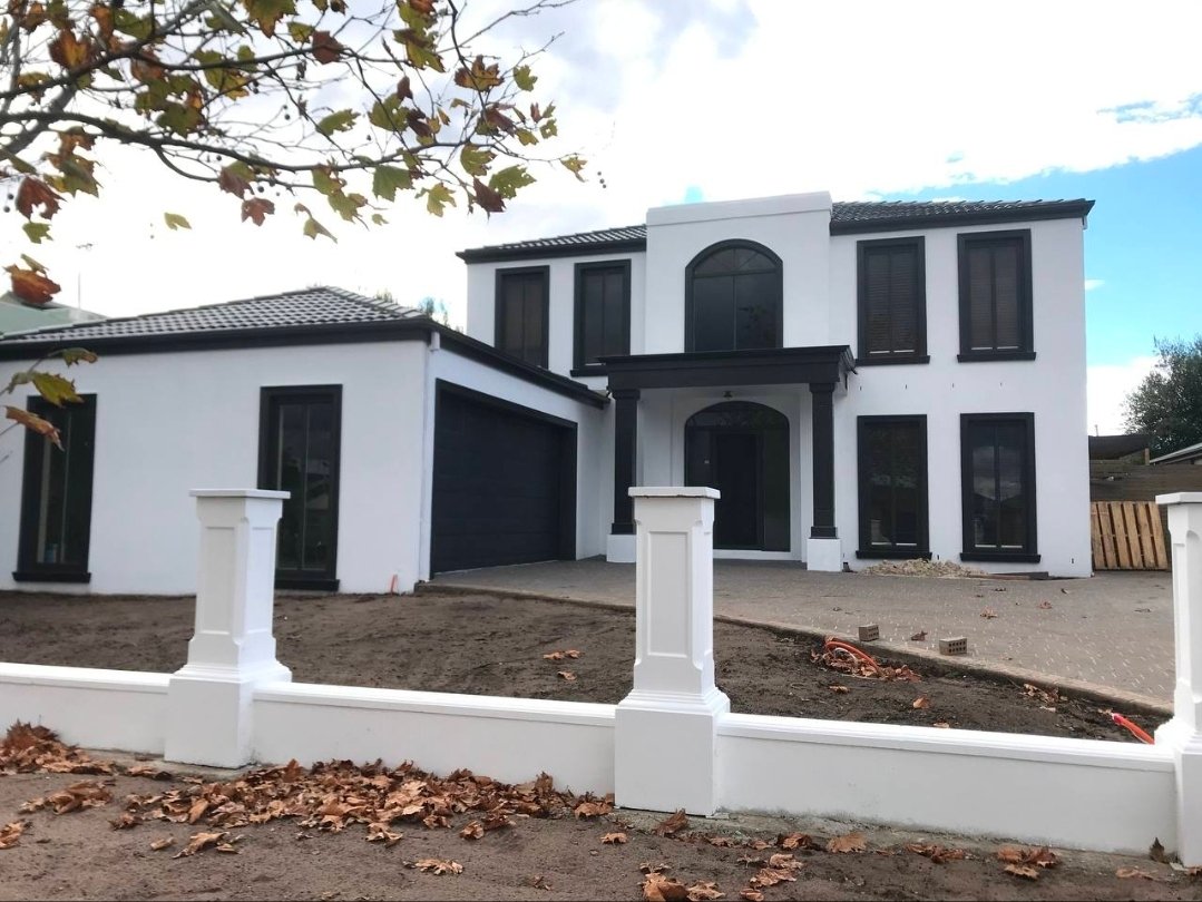 After exterior painting photo of the same two-storey house repainted white with dark trim