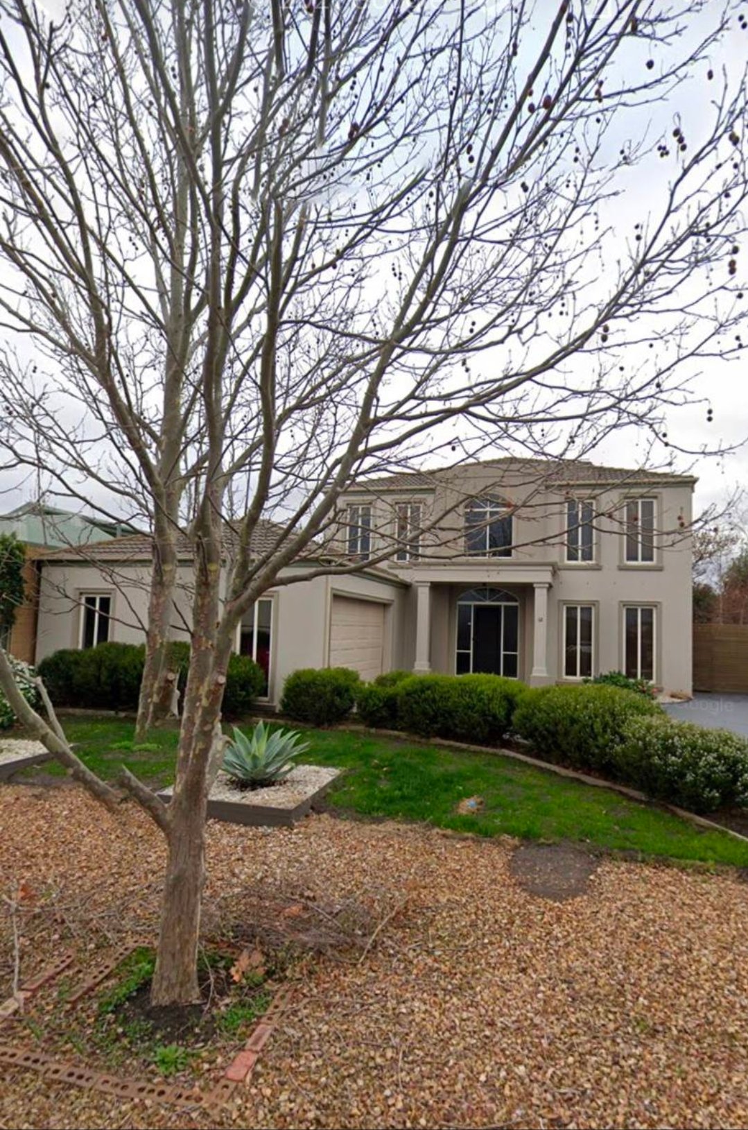 Before exterior painting photo of a two-storey house with beige walls and older facade finish