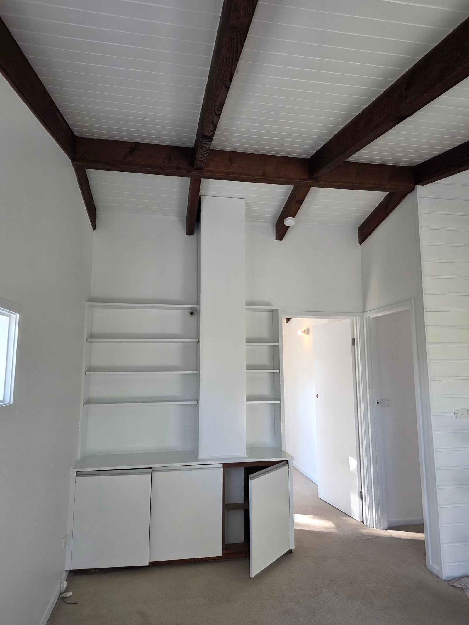 After interior repaint photo showing the same room with fresh white-painted walls, shelves, and ceiling panels