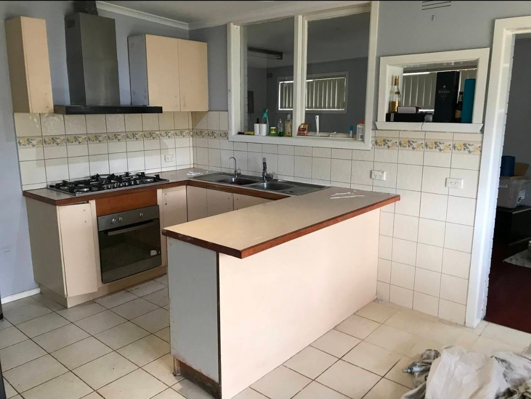 Before kitchen refresh photo showing dated beige cabinets, tiled splashback border, and older finishes